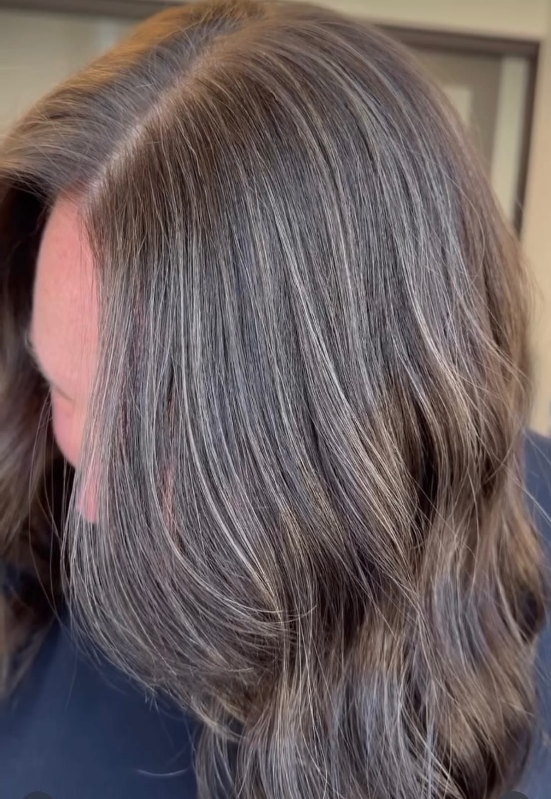 After — the same hair with silver blended through a cool brown, the grey softened into dimensional waves