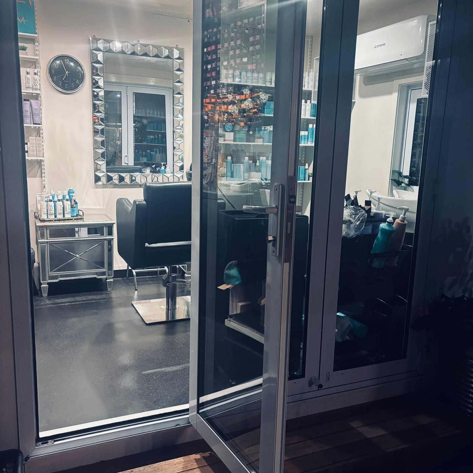 The doorway into the salon — one chair, one mirror, the shelf of tonal products beyond